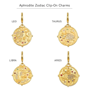 Detail of four gold zodiac charms with embossed icons and colorful zircons on white background