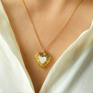 Vintage heart locket necklace with floral engraving and opal stone on a model