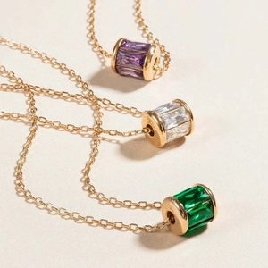 Three birthstone cylinder necklaces in gold finish with purple, white and green gems