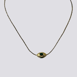 Detailed shot of vintage Nepal style pendant with green gemstone and red accents