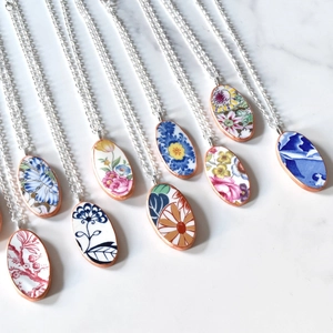 Detailopname van vintage ovale bloemenhangers met keramische patronen op marmer