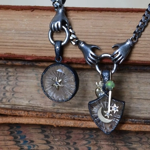 Detail von handförmigem Verschluss und Himmelsanhängern an einer alten Metallkette