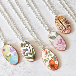 Detail van vijf vintage ovale bloemenhangers in porseleinstijl op een stenen achtergrond