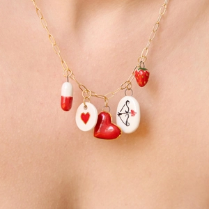 Primer plano de collar chapado en oro de 18K con colgantes de corazón y fresa