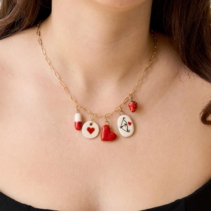 Primer plano de collar chapado en oro 18K con dijes de corazón y fresa en una modelo