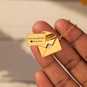 Detail van de gouden enveloppe ketting met een gegraveerde kaart van mama