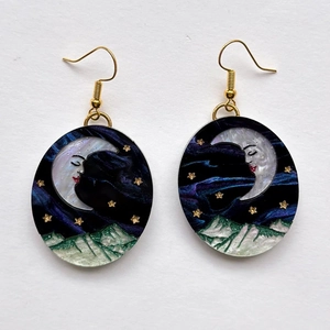 Detail of oval drop earrings with celestial moon, starry night sky, and snowy mountain design