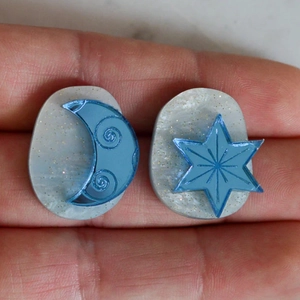 Detailed close-up of crescent moon and star resin earrings with gold glitter accents