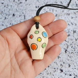 Macro view of a colorful hand-painted ceramic vase pendant on a black adjustable cord