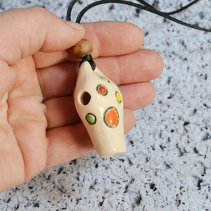 Close-up of a handmade ceramic vase pendant necklace with colorful dots and wooden bead