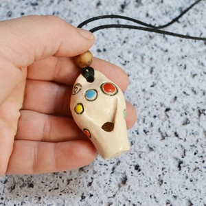 Detail of a ceramic whistle pendant with six colorful stones and a black cord