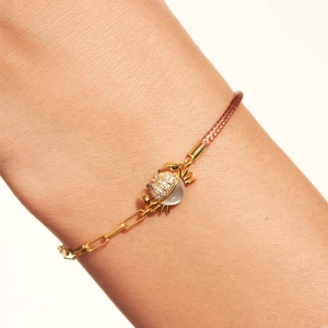 Detalle de pulsera de cangrejo con cordón rojo, cadena de clip y piedras blancas