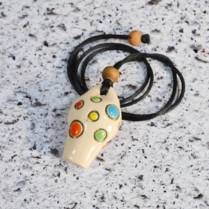 Macro detail of white ceramic ocarina with colorful holes and black woven neck strap