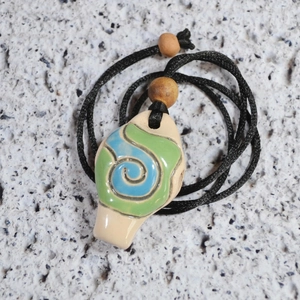 Detail macro shot of a glazed ceramic vase pendant with blue swirls on a stone surface