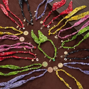 Close-up of colorful paisley fabric necklaces featuring varied lucky alloy charms