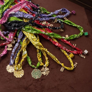 Macro detail of colorful silk scarves necklaces with golden good luck lucky charms