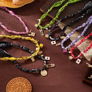Detail of colorful silk scarf necklaces with lucky charms like dice and keys