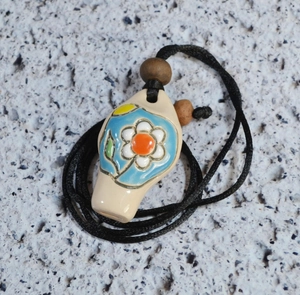 Handcrafted ceramic whistle necklace with blue flower pendant and black woven cord