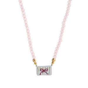 Close-up van roze kralenketting met rechthoekige keramische strikhanger en gouden sluiting