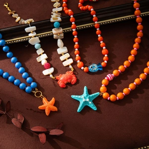 Macro detail of ocean-themed beaded necklace with starfish, crab, and shell pendants