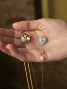 Détail d'un collier pendentif cœur émaillé ouvrant avec une perle blanche à l'intérieur