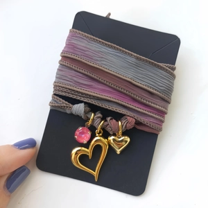 Boho-Halskette mit Herzanhängern und rosa Kristall auf einer schwarzen Präsentationskarte