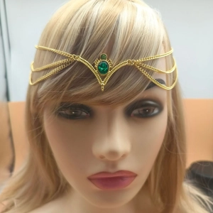 Close-up of golden bridal head chain with green gemstones and boho tassel design