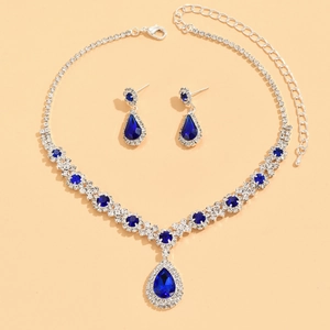 Detailed view of silver necklace and teardrop crystal earrings set in deep blue finish