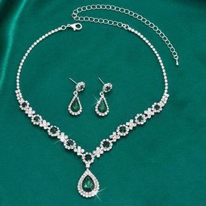 Detail of silver waterdrop jewelry set with emerald green stones on green silk