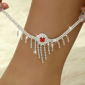 Détail de la chevillère à glands en strass rouges sertie d'argent sur la cheville