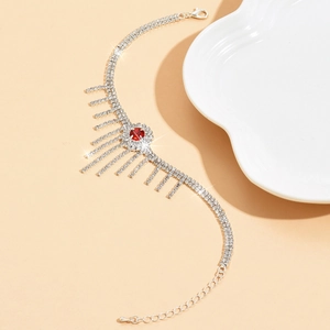 Bracelet de cheville argenté à franges avec strass rouge sur un fond beige neutre