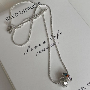 Detail of silver fishbone chain with colorful zircon ring and engraved forever bead