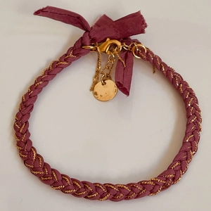 Detail of bohemian red woven bracelet with gold lobster clasp and round charm pendant
