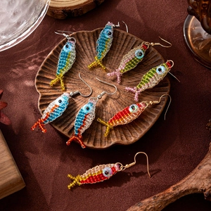 Handmade colorful beaded fish earrings in four vibrant patterns on a stylish wood tray
