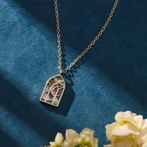 Makroaufnahme von gotischem Bogenanhänger mit schimmernder Einlage und Goldkette