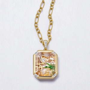 Primer plano de relicario de cristal dorado con letras LOVE y dije de palmera