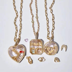 Dettaglio di medaglioni dorati apribili con charms MAMA e pendenti fai-da-te assortiti
