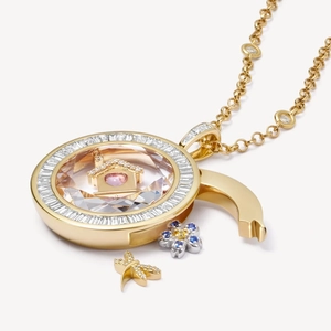 Dettaglio di un medaglione in oro 18K con casa in miniatura e cuore nel cristallo