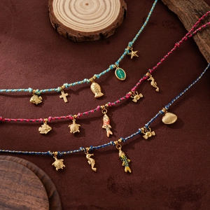 Dettaglio di collane in corda colorata intrecciata con ciondoli marini e croci dorate