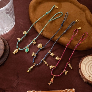 Dettaglio di braccialetti intrecciati colorati con ciondoli dorati a forma di pesce