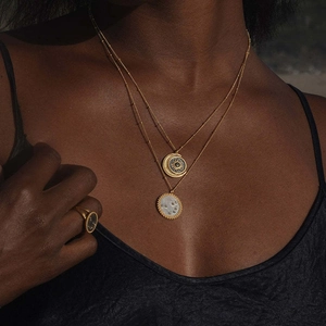Golden layered necklace with sun moon charms and circular disc pendant on female model