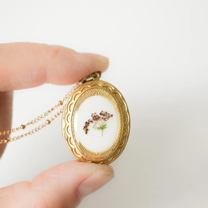 Detailansicht eines ovalen 14k Goldmedaillons mit echten Trockenblumen und Gravur