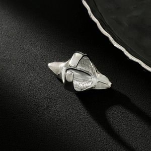 Vista macro di un anello geometrico argento con finitura lucida e design aperto regolabile
