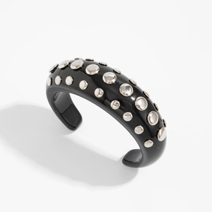 Close-up of a black resin punk bracelet with silver metal studs and open C-shape design