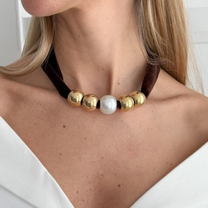 Detailopname van luipaardprint fluwelen choker met witte parel en gouden kralen op model