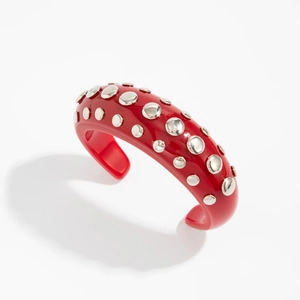 Close-up of a red resin open cuff bracelet featuring silver metal rivet stud embellishments