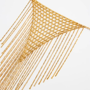 Macro detail of golden woven mesh chain necklace with long tassels in punk metal style