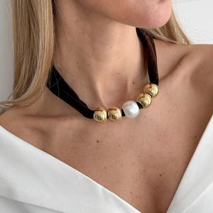 Detail van vintage fluwelen choker met gouden kralen en een grote witte parel