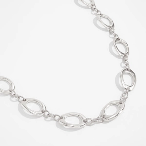 Close-up detail of geometric silver metal waist chain with hollow oval and round link design