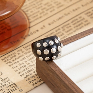 Macro side view of a black punk resin ring with silver studs on a vintage wooden box